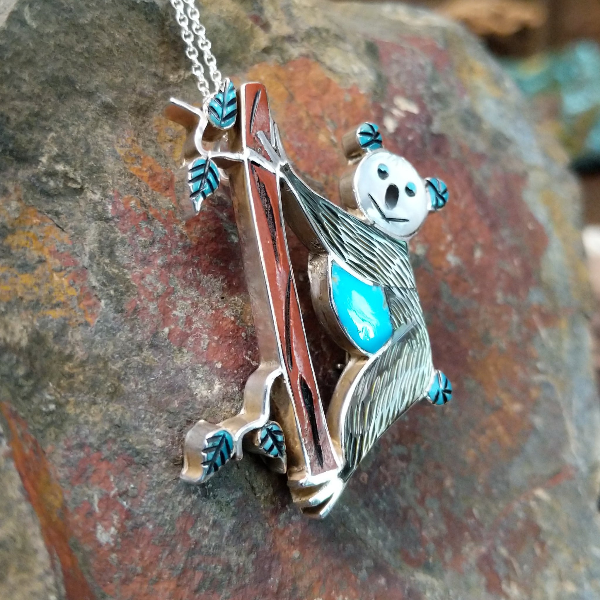Handcrafted sterling silver koala pin and pendant by Valerie Comozona, featuring detailed inlay and a convertible pin-to-pendant design; side view.