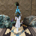 Navajo-made Kokopelli kachina doll by M. C. with blue headdress, peacock feathers, flute, and gray garments.