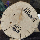 Underside of M. C. kokopelli kachina doll showing handwritten signature and label on wood base.