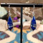 Handcrafted Navajo sterling silver dangle earrings by Cathy Webster featuring deltoid-shaped lapis inlay with polished sterling silver channel accents on French hooks.