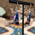 Handcrafted Navajo sterling silver dangle earrings by Cathy Webster featuring deltoid-shaped lapis inlay with polished sterling silver channel accents on French hooks; side view.