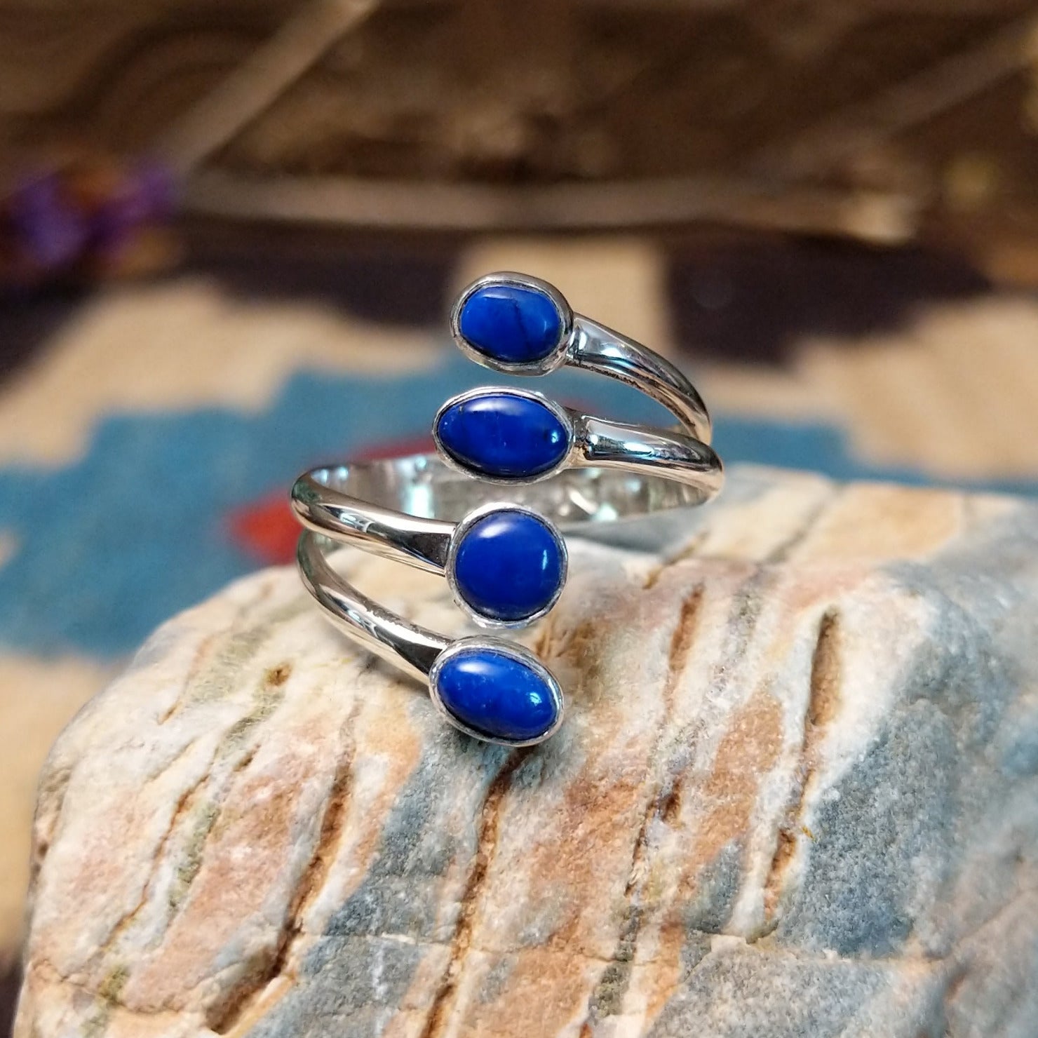 Sterling silver ring with lapis set in four bezels, each suspended on the strands of the band.
