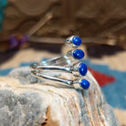 Sterling silver ring with lapis set in four bezels, each suspended on the strands of the band.