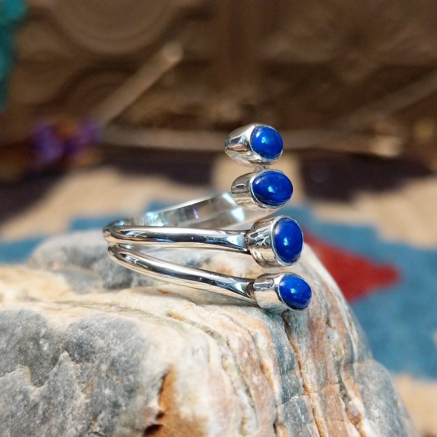 Sterling silver ring with lapis set in four bezels, each suspended on the strands of the band.