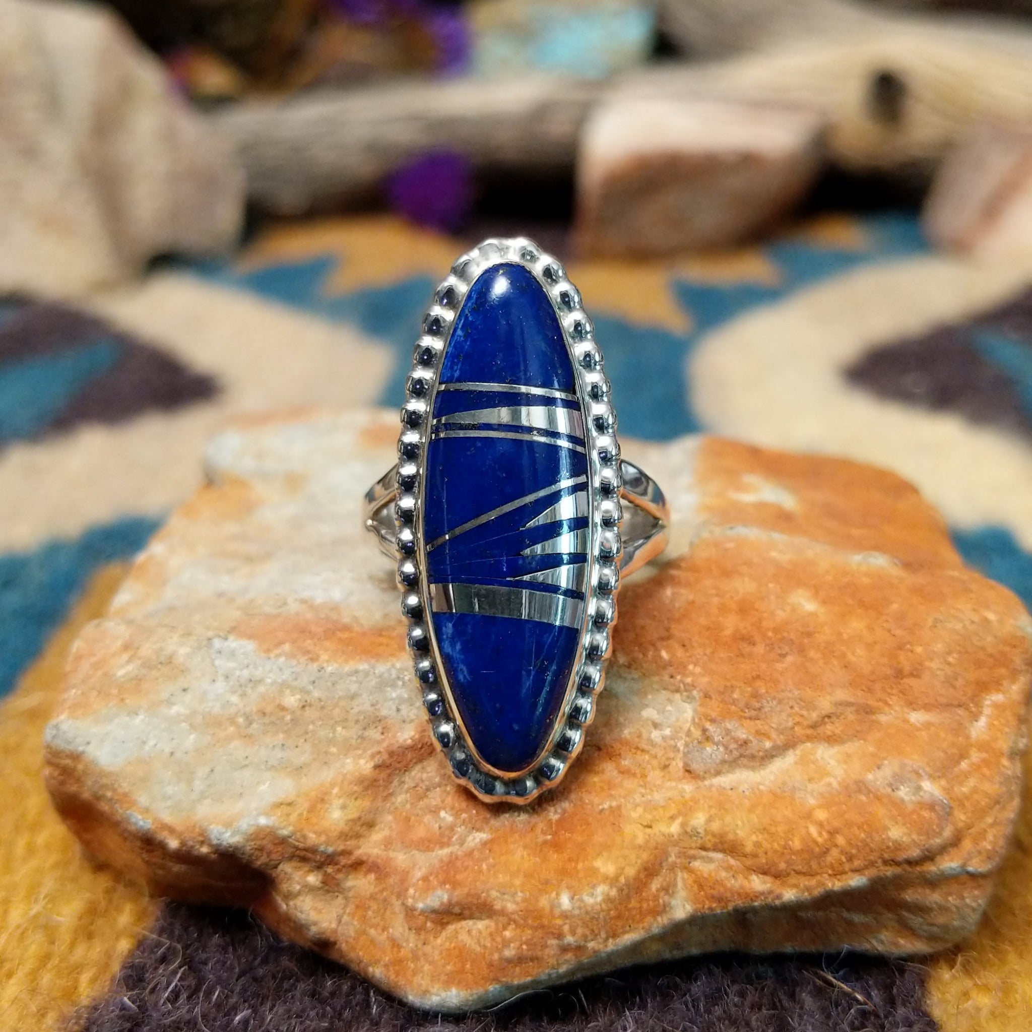 Handcrafted sterling silver ring featuring an elongated marquise-shaped lapis lazuli inlay with diagonal sterling silver geometric accents, framed by a beaded silver border and set on a split sterling silver band.