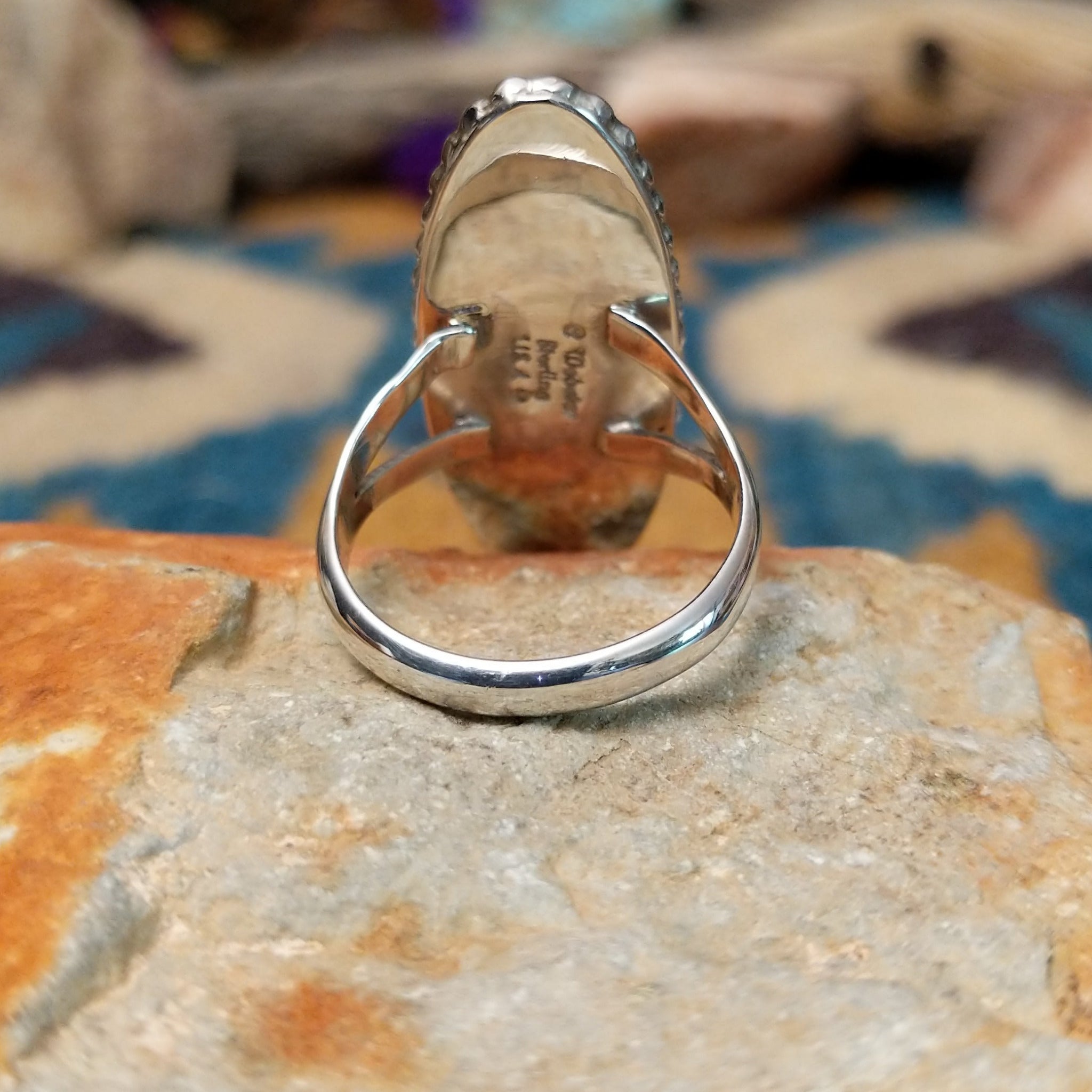 Handcrafted sterling silver ring featuring an elongated marquise-shaped lapis lazuli inlay with diagonal sterling silver geometric accents, framed by a beaded silver border and set on a split sterling silver band; underside view.