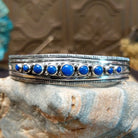 Sterling silver cuff bracelet with lapis set in bezels lined across the surface and stamping.