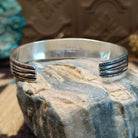 Sterling silver cuff bracelet with lapis set in bezels lined across the surface and stamping.