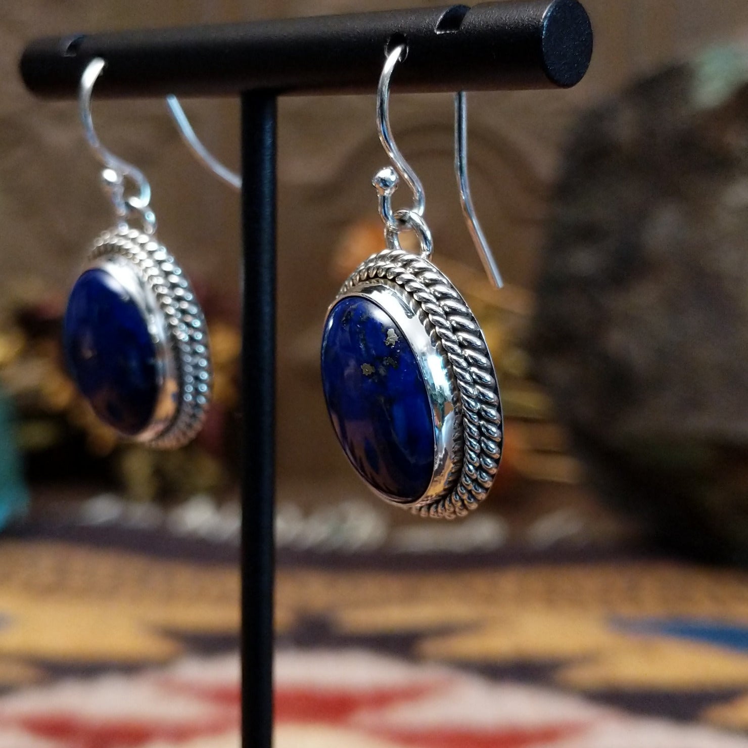 Sterling silver lapis lazuli dangle earrings featuring oval blue stones with twisted rope detailing and French hooks.