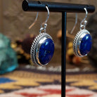 Sterling silver lapis lazuli dangle earrings featuring oval blue stones with twisted rope detailing and French hooks.