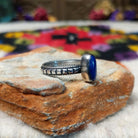 Elegant Lapis Oval Ring by Elgin Tom with an elongated deep blue lapis stone set in sterling silver with twisted-rope edging and oxidized band details; side view.