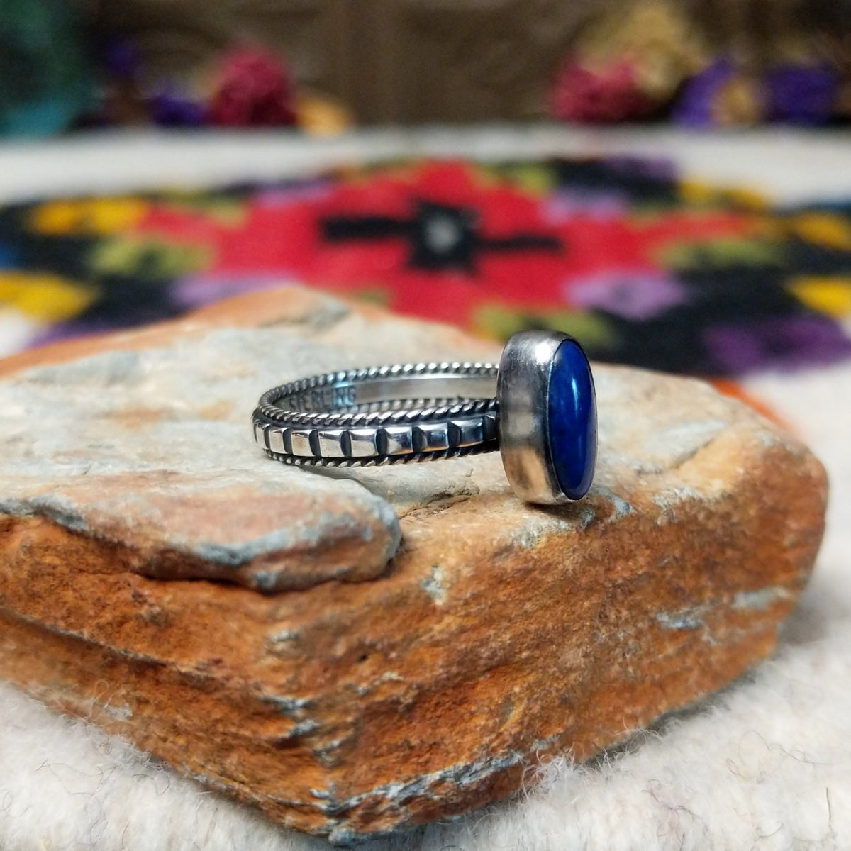 Elegant Lapis Oval Ring by Elgin Tom with an elongated deep blue lapis stone set in sterling silver with twisted-rope edging and oxidized band details; side view.