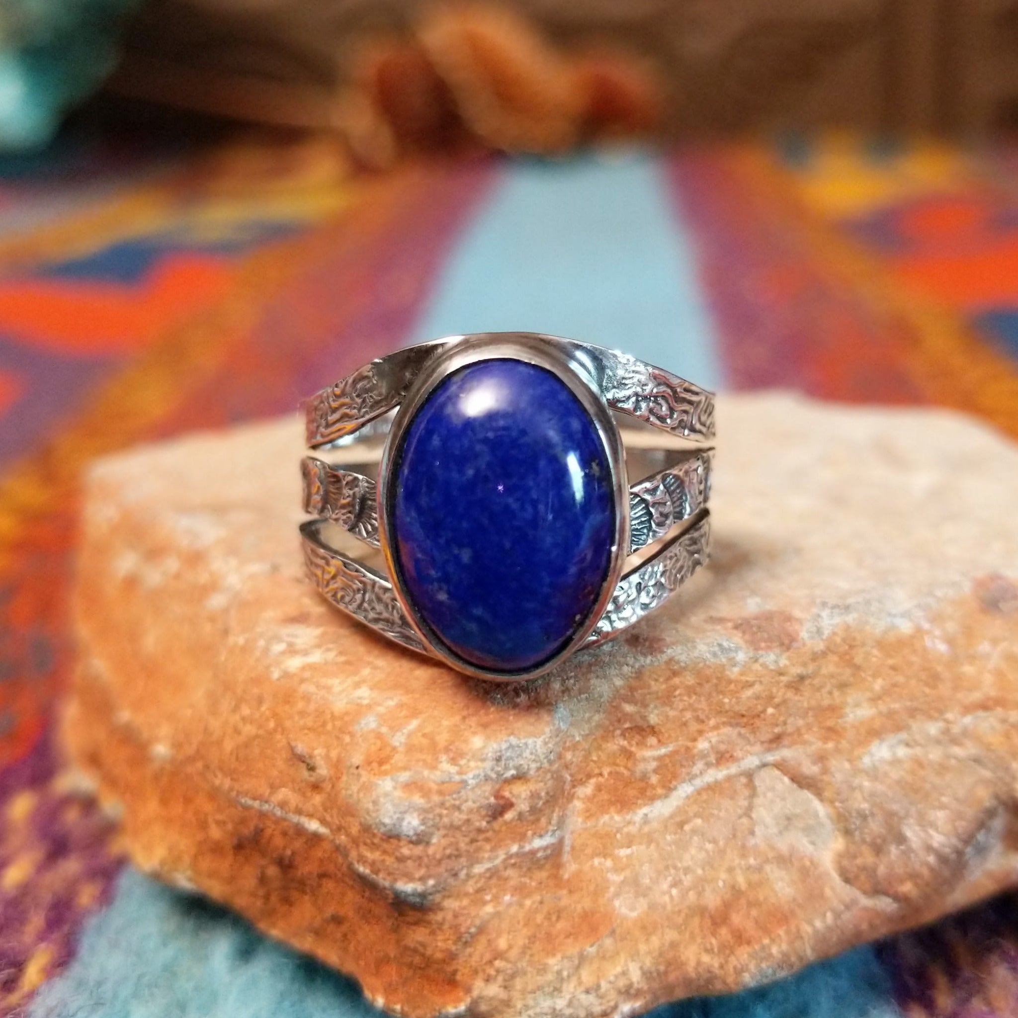 Lapis Oval Ring by Raymond Coriz featuring a large oval blue lapis stone set in Sterling Silver with a split band and intricate stamped detailing.