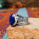 Lapis Oval Ring by Raymond Coriz featuring a large oval blue lapis stone set in Sterling Silver with a split band and intricate stamped detailing; side view.