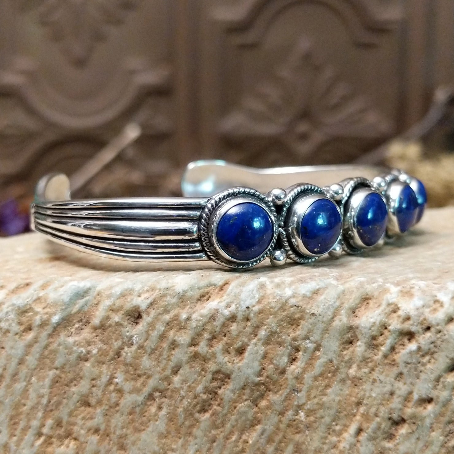 Sterling silver cuff bracelet with lapis set in a quintet of round bezels, framed by twisted rope and dotted accents.