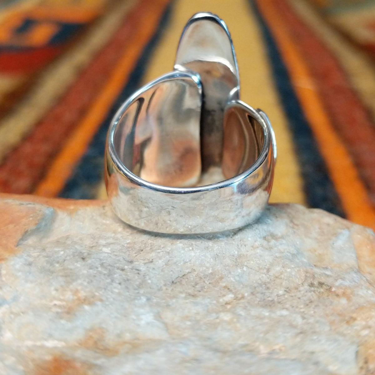 Lapis Ring by J. Chee featuring an elongated oval royal blue lapis lazuli stone set in sterling silver with a twisted rope bezel and decorative scalloped side accents; underside view.