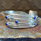 Sterling silver cuff bracelet with layered strands and lapis set in bezels across the surface.