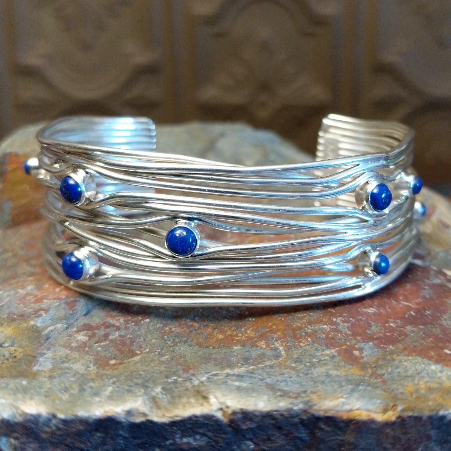 Sterling silver cuff bracelet with layered strands and lapis set in bezels across the surface.