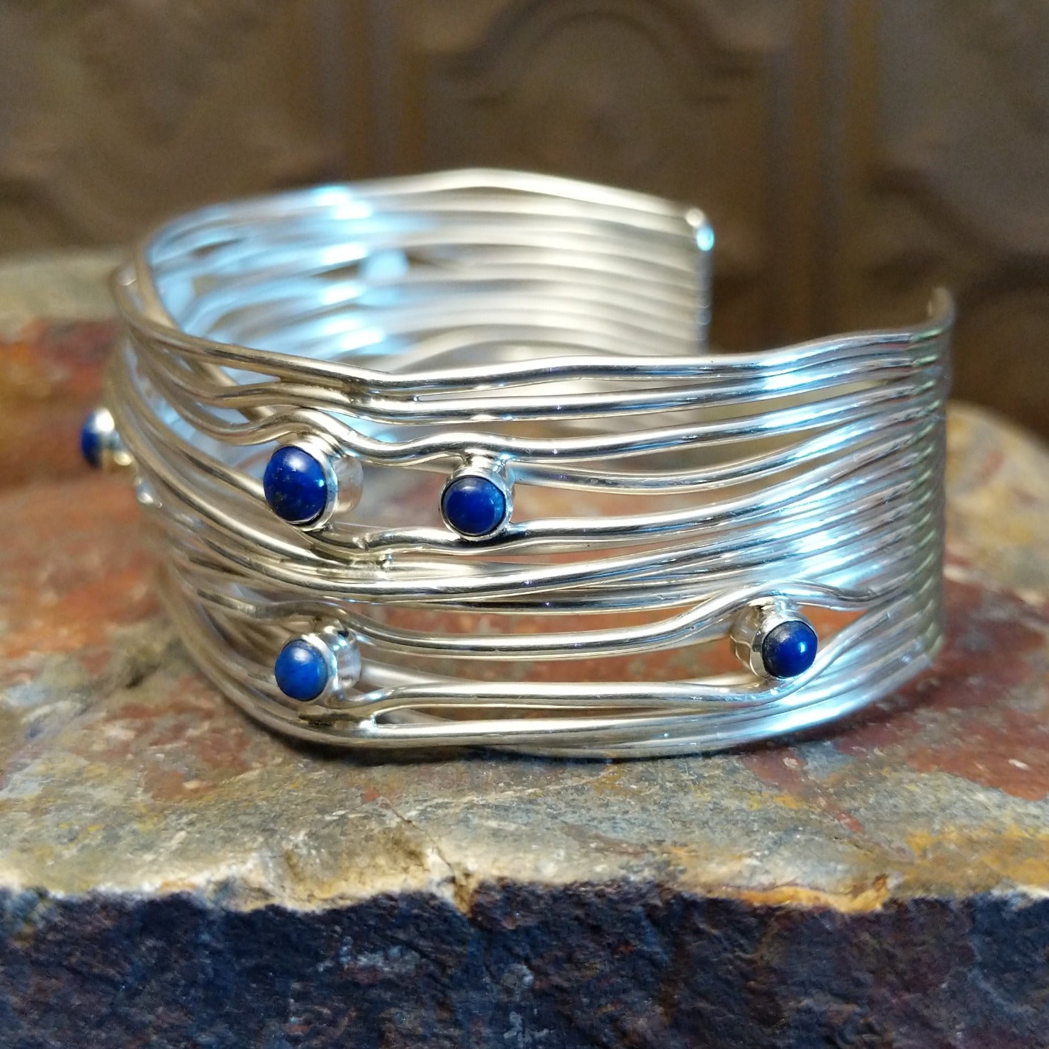 Sterling silver cuff bracelet with layered strands and lapis set in bezels across the surface.