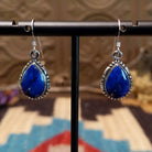 Sterling silver earrings with lapis set in teardrop bezels, framed by ornate silverwork.