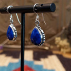Sterling silver earrings with lapis set in teardrop bezels, framed by ornate silverwork.