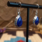 Sterling silver earrings with lapis set in teardrop bezels, framed by ornate silverwork.
