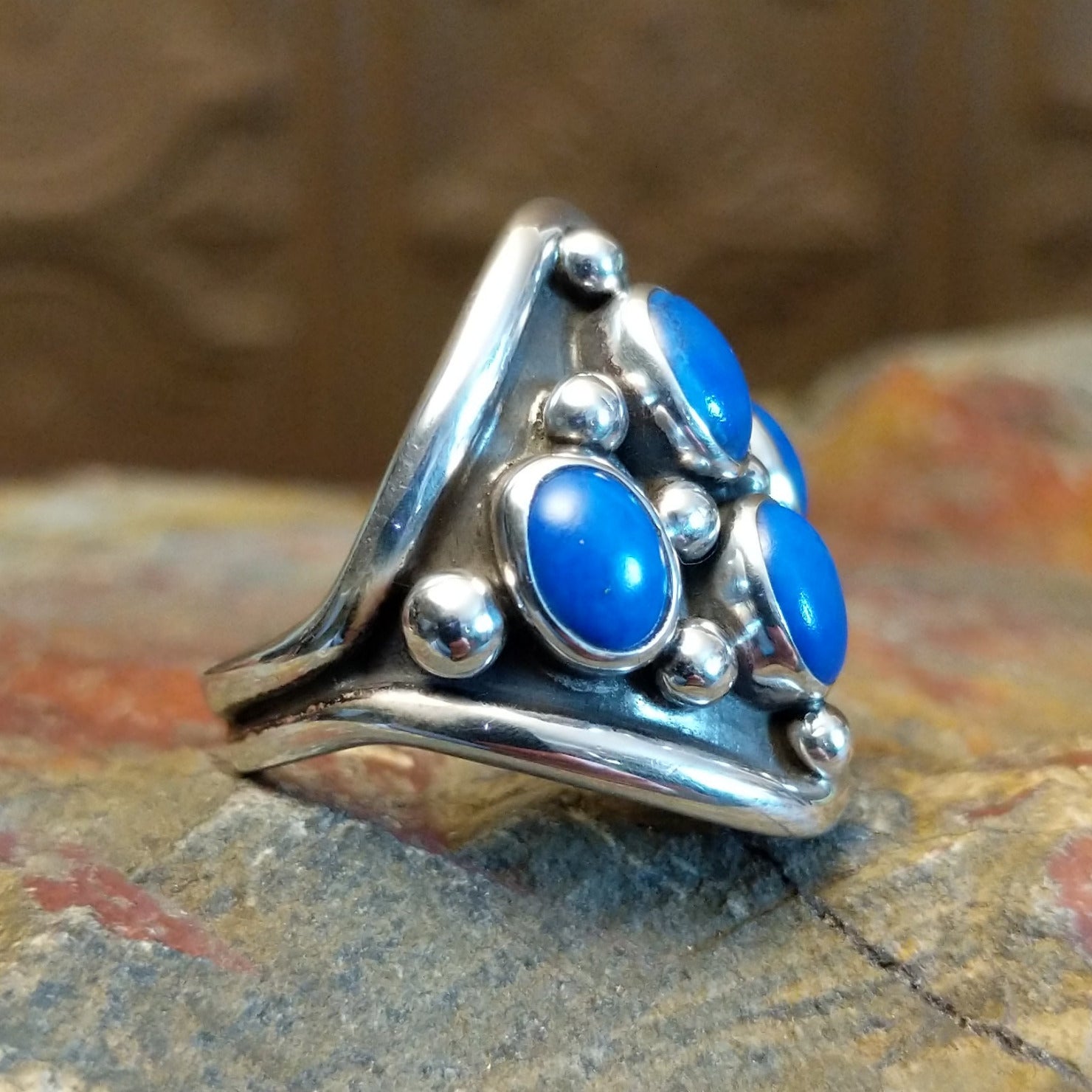 Sterling silver ring with lapis set in tetrad bezels along the surface and dotted accents.