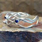 Sterling silver cuff bracelet with interwoven strand band and lapis set in scattered bezels.
