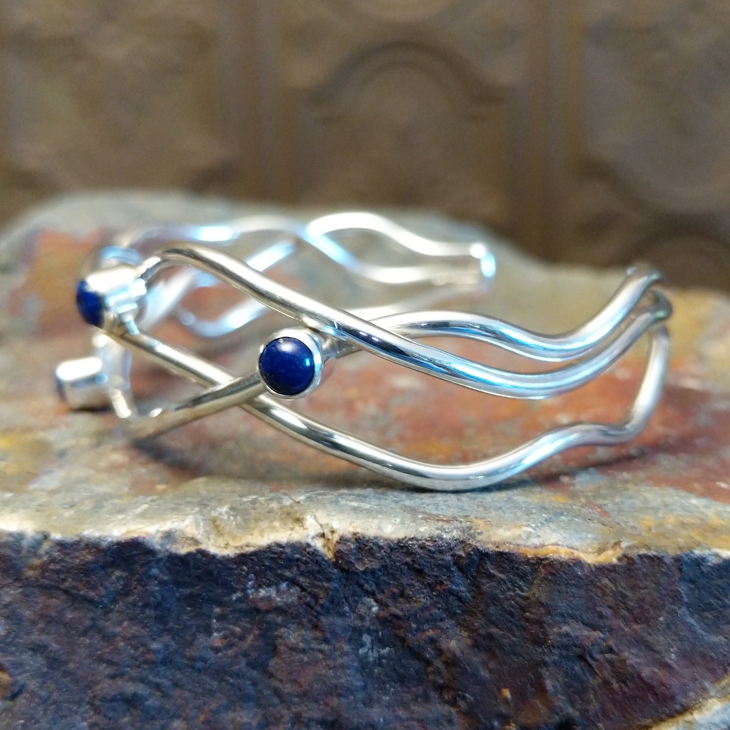 Sterling silver cuff bracelet with interwoven strand band and lapis set in scattered bezels.