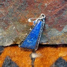 Sterling silver triangular pendant with lapis set in the bezel, framed by incised stamping.