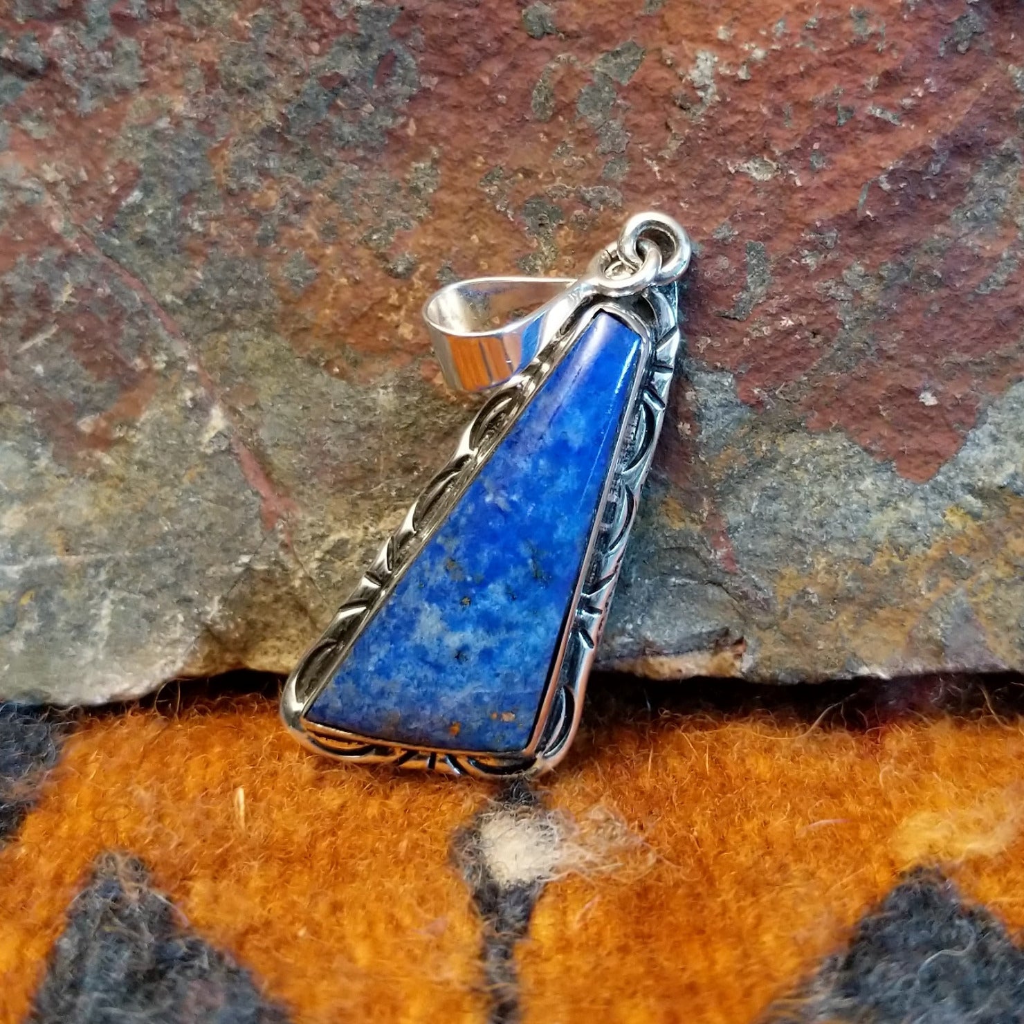 Sterling silver triangular pendant with lapis set in the bezel, framed by incised stamping.