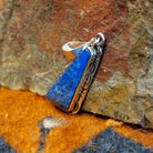 Sterling silver triangular pendant with lapis set in the bezel, framed by incised stamping.