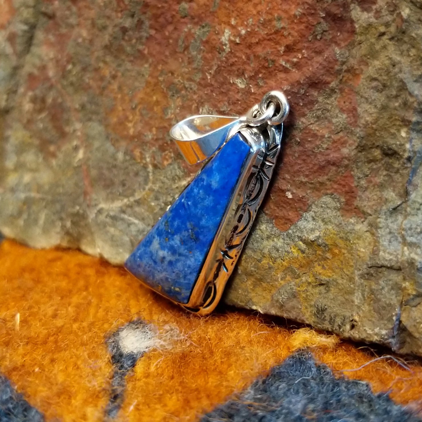 Sterling silver triangular pendant with lapis set in the bezel, framed by incised stamping.