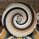 Handwoven large earth tone wire art bowl by Bridge for Africa featuring a spiral pattern in recycled wire with ivory, beige, taupe, gray, brown, and black tones, perfect for home décor or wall display.