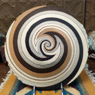 Handwoven large earth tone wire art bowl by Bridge for Africa featuring a spiral pattern in recycled wire with ivory, beige, taupe, gray, brown, and black tones, perfect for home décor or wall display; underside view.