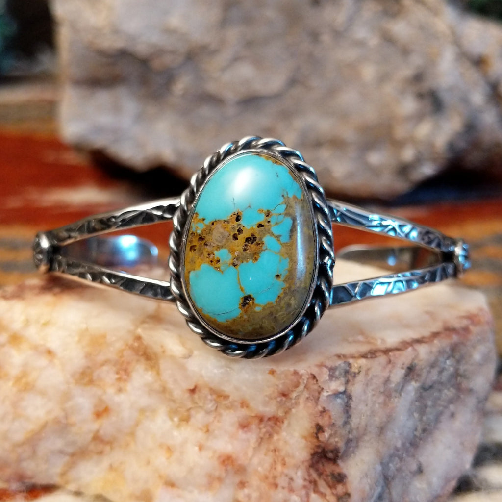 Sterling silver cuff with stamped designs and turquoise set in a twisted rope bezel.