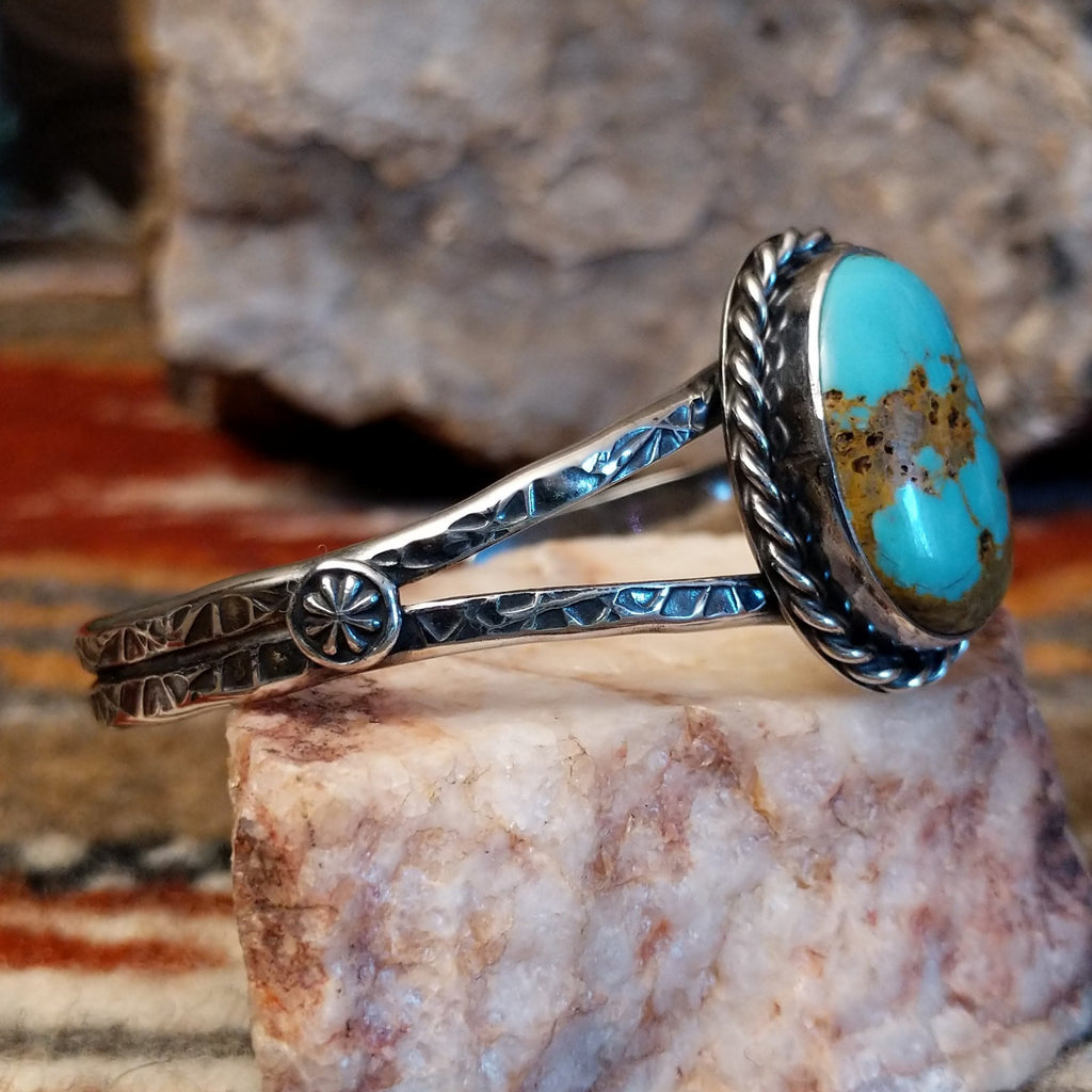 Sterling silver cuff with stamped designs and turquoise set in a twisted rope bezel.