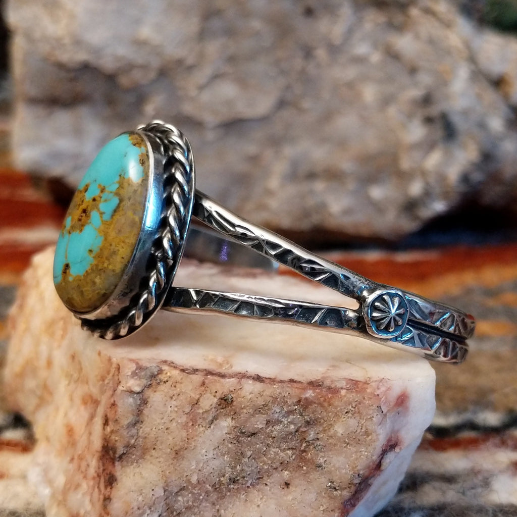 Sterling silver cuff with stamped designs and turquoise set in a twisted rope bezel.
