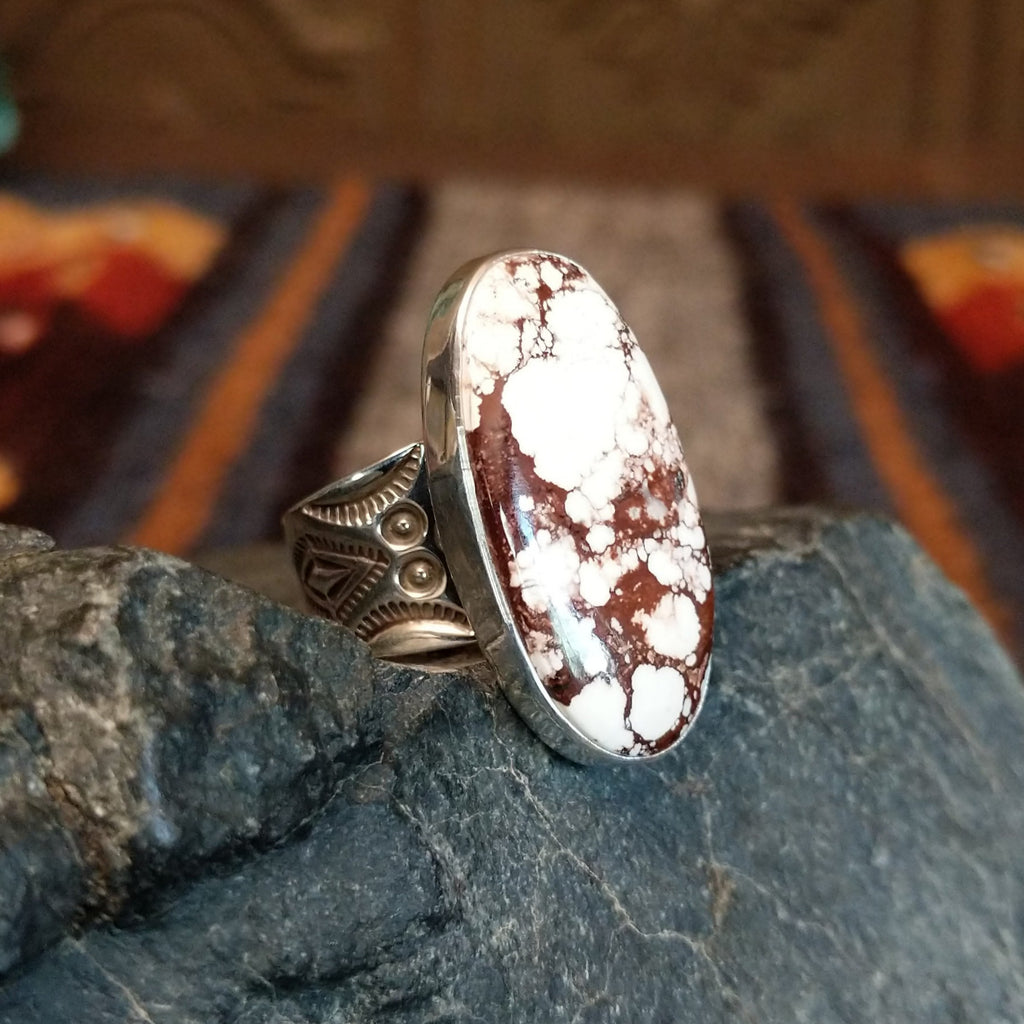 Oval ring set in silver with intricate band detailing.