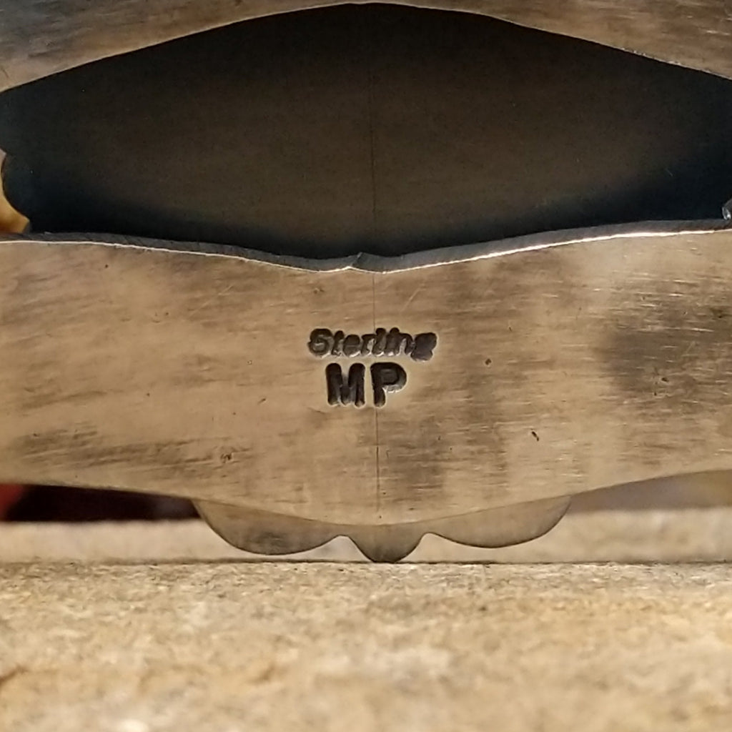 The inside of the cuff features the artist's stamp.