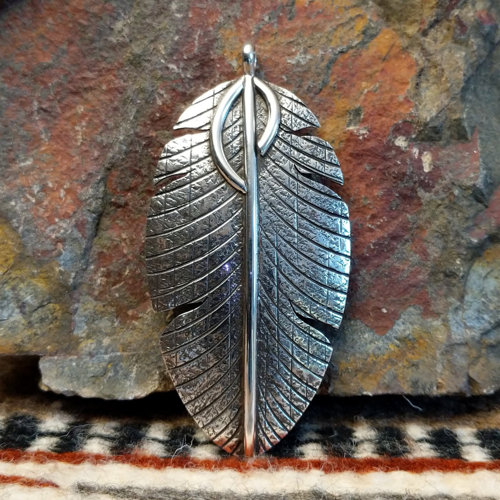 Large sterling silver feather pendant with intricate hammered detailing.