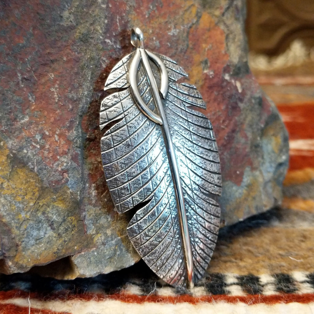 Large sterling silver feather pendant with intricate hammered detailing.