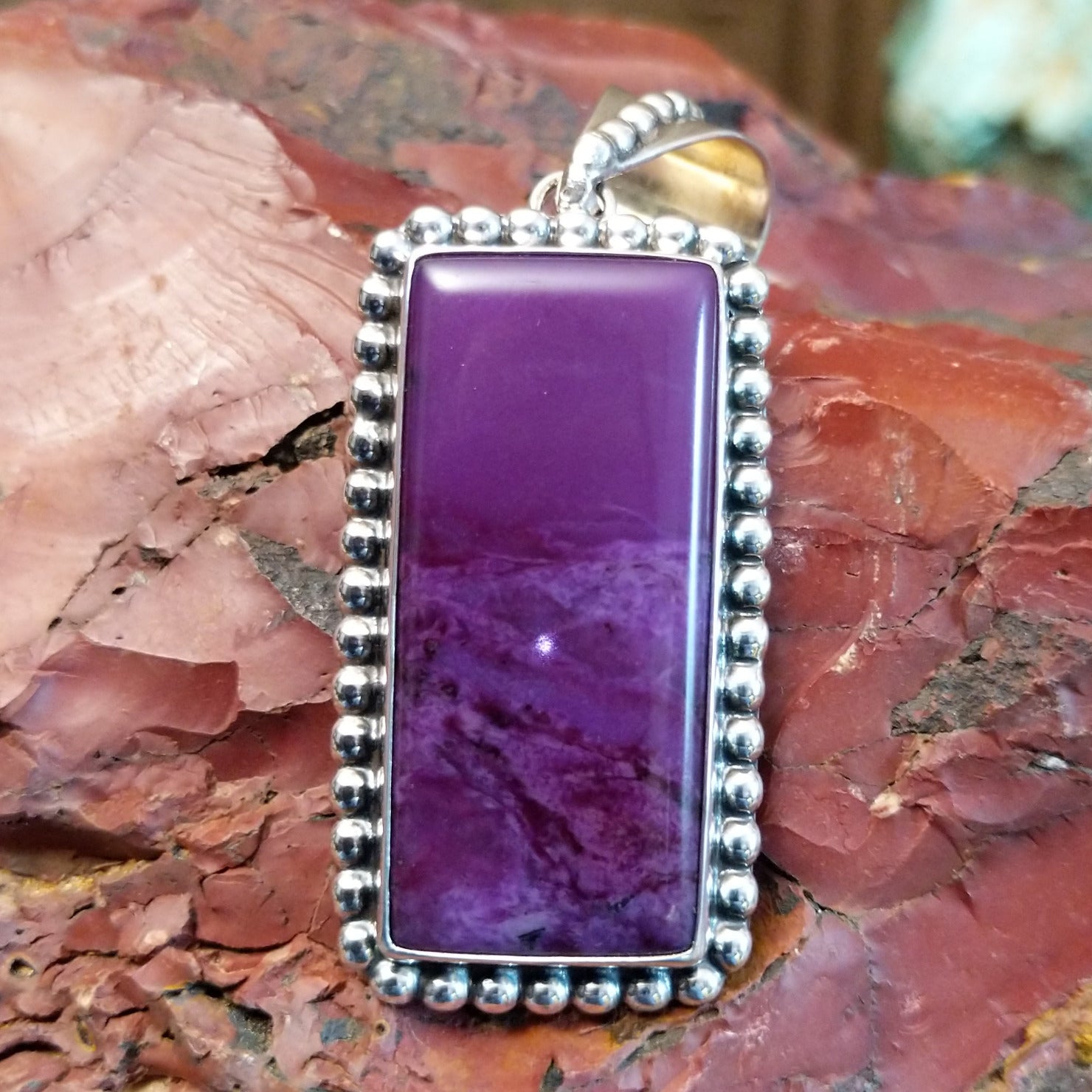 Sterling silver pendant with rectangular sugilite framed by dotted accents.