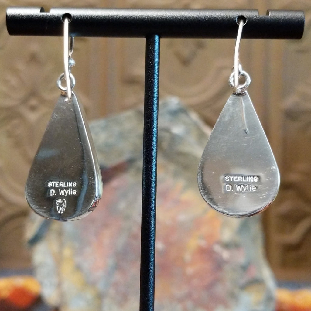 The back of the polished sterling silver earrings featuring the artist's stamp and authentication.