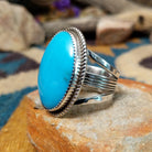 Handcrafted sterling silver Navajo ring by Alvin Joe featuring a large oval natural turquoise cabochon with subtle matrix, set in a classic twisted rope bezel; side view.