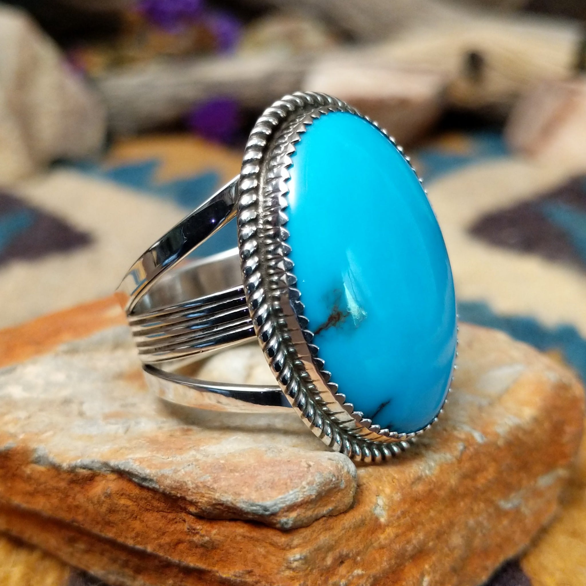 Handcrafted sterling silver Navajo ring by Alvin Joe featuring a large oval natural turquoise cabochon with subtle matrix, set in a classic twisted rope bezel; side view.