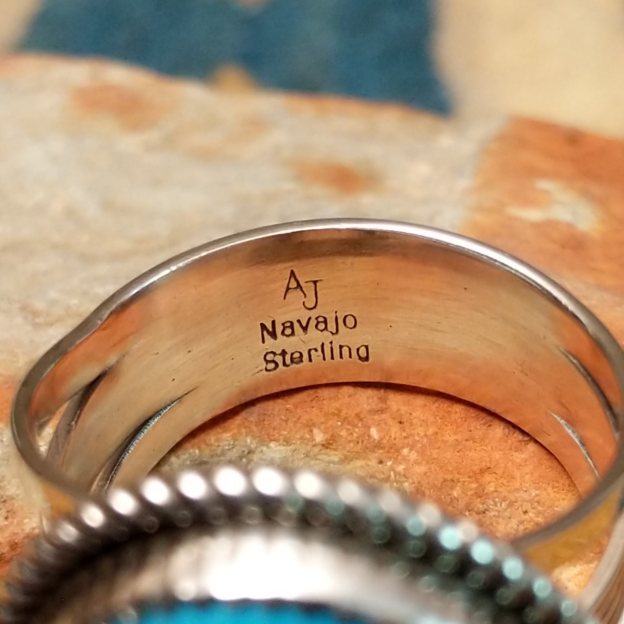 Handcrafted sterling silver Navajo ring by Alvin Joe featuring a large oval natural turquoise cabochon with subtle matrix, set in a classic twisted rope bezel; artisan, tribe, and Sterling Silver stamp.