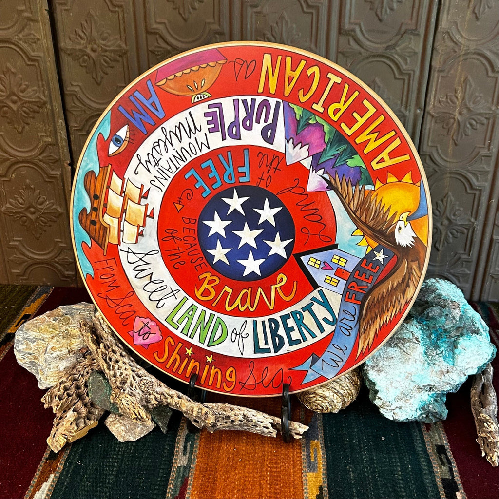 Wooden lazy susan with decorative designs such as patriotic symbolism of the USA eagle, ship, and lyrics painted in vibrant colors.
