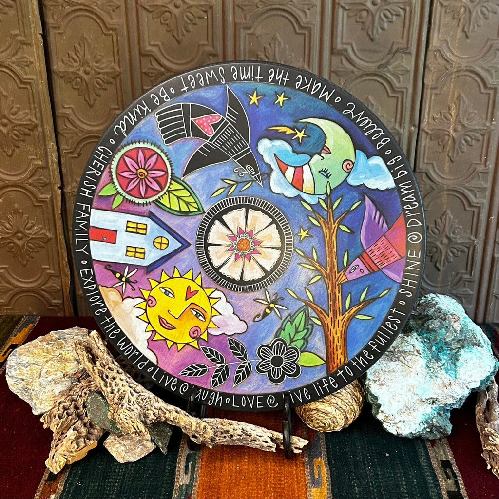 Wooden lazy susan with decorative designs such as the night sky, birds, trees, and more that are painted vibrant colors.