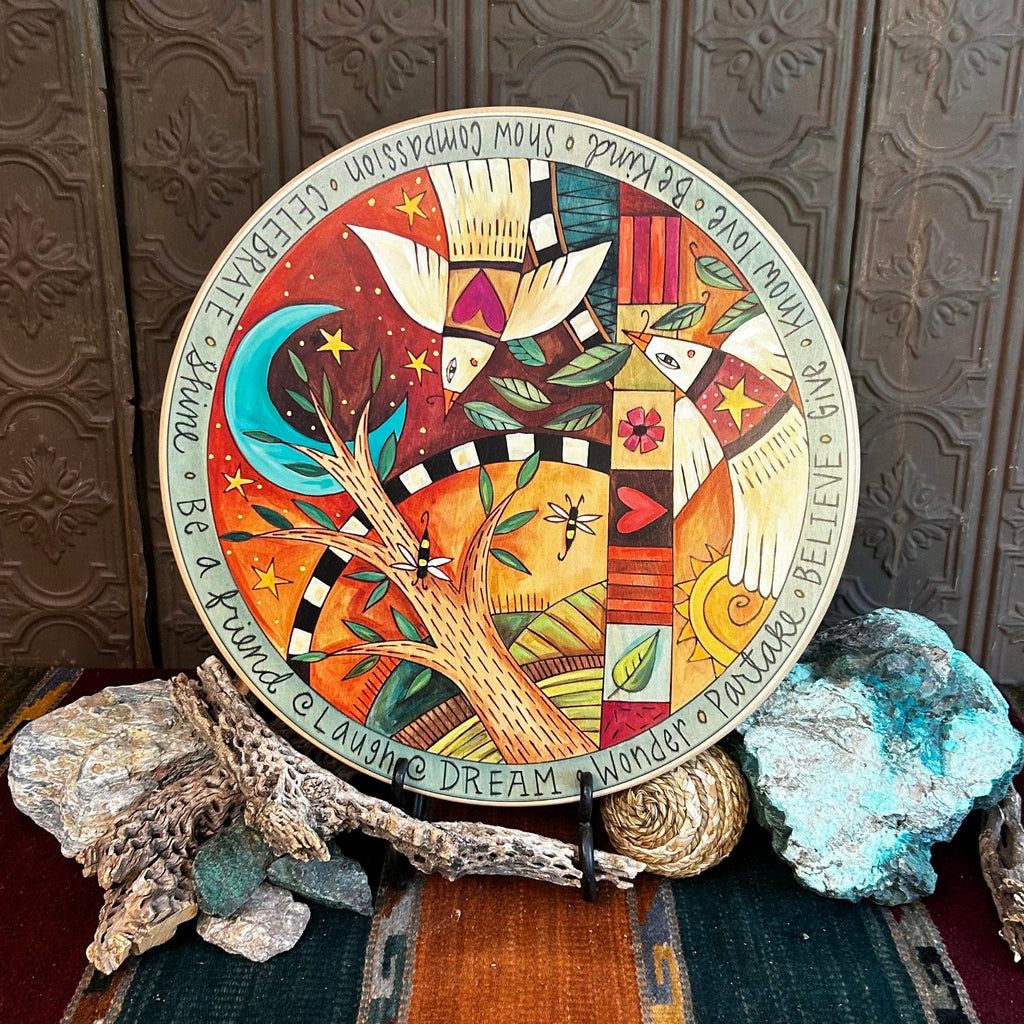 Wooden lazy susan with decorative designs such as birds, red tones, trees, and hills vibrantly painted.